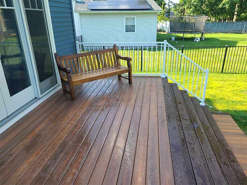 A wooden deck with a bench and stairs leading up to it.