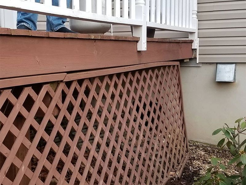 A wooden deck with a white railing and a lattice fence
