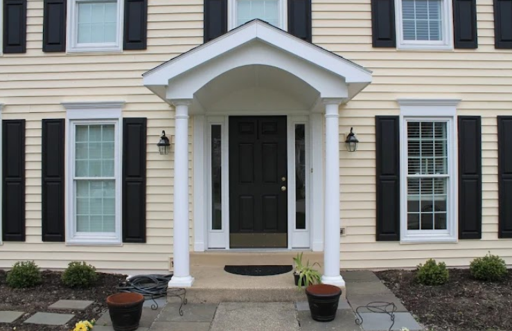 A large deck with a white railing and stairs in front of a house.