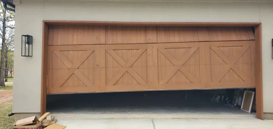 A wooden garage door is open on a house.