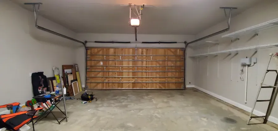 An empty garage with a garage door open and a ladder.