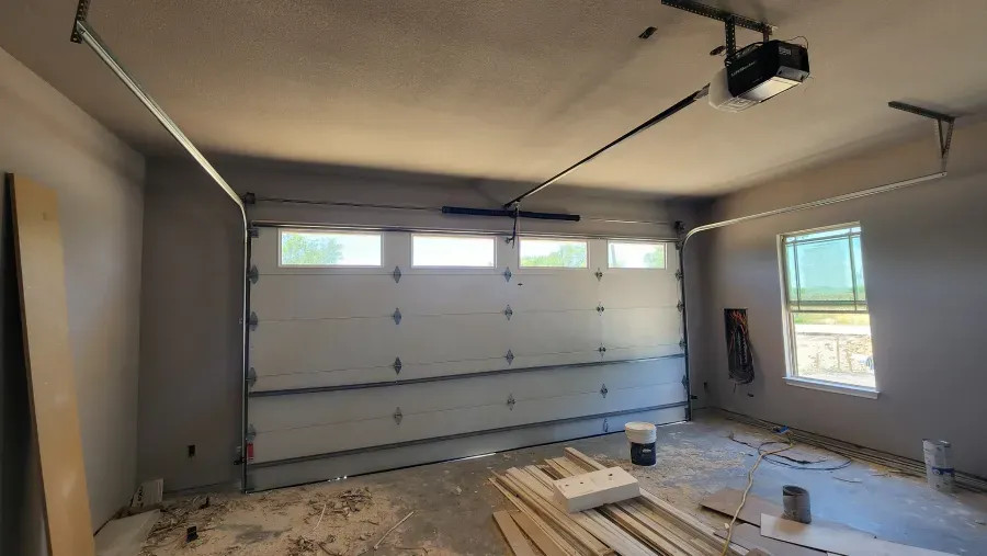 An empty garage with a garage door open and a window.