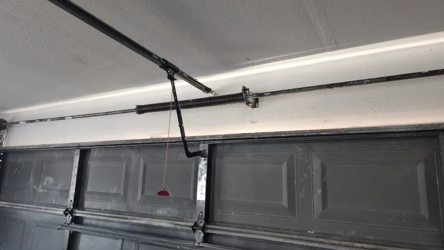 A garage door opener is hanging from the ceiling of a garage.