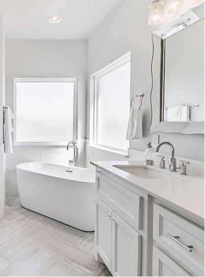 Bright white bathroom with a freestanding bathtub, vanity, and large windows.
