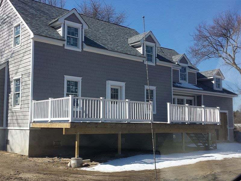 A gray house with a white deck in front of it