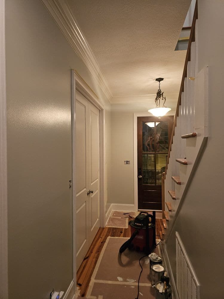 A hallway with stairs and a vacuum cleaner in it