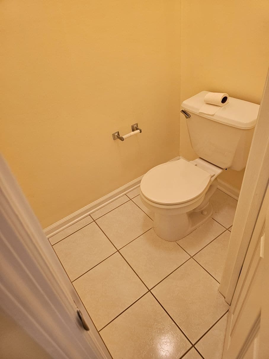A toilet is sitting in a small bathroom next to a door.