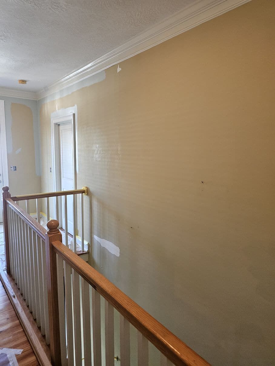A hallway with a wooden railing and a door.