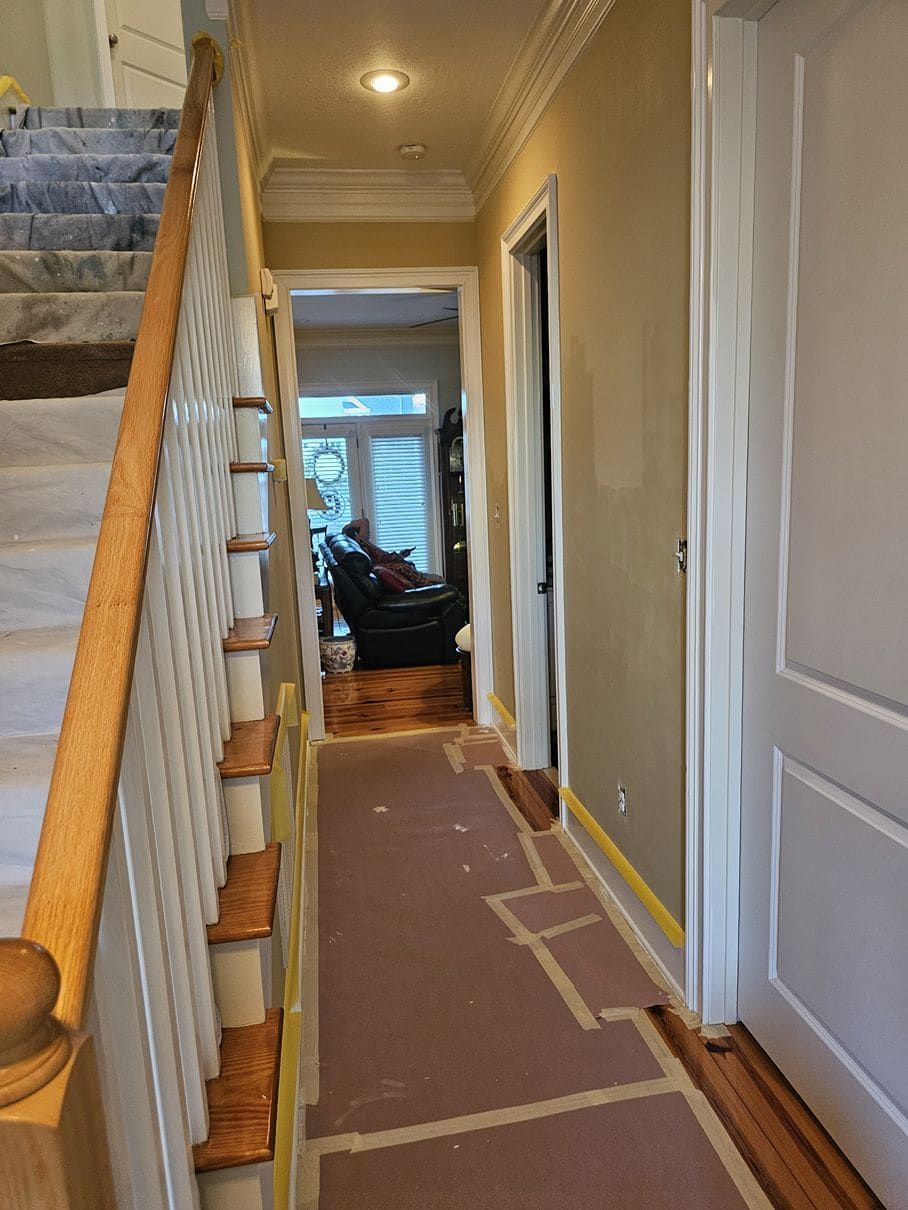 A hallway with stairs and a living room in the background