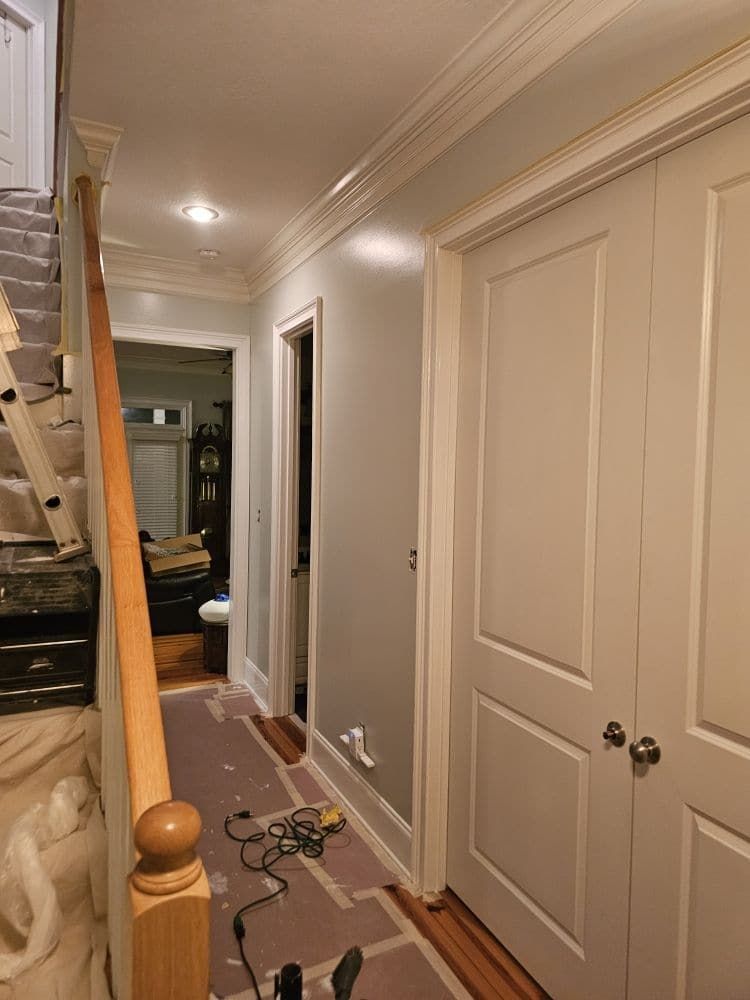 A hallway with white doors and a wooden railing
