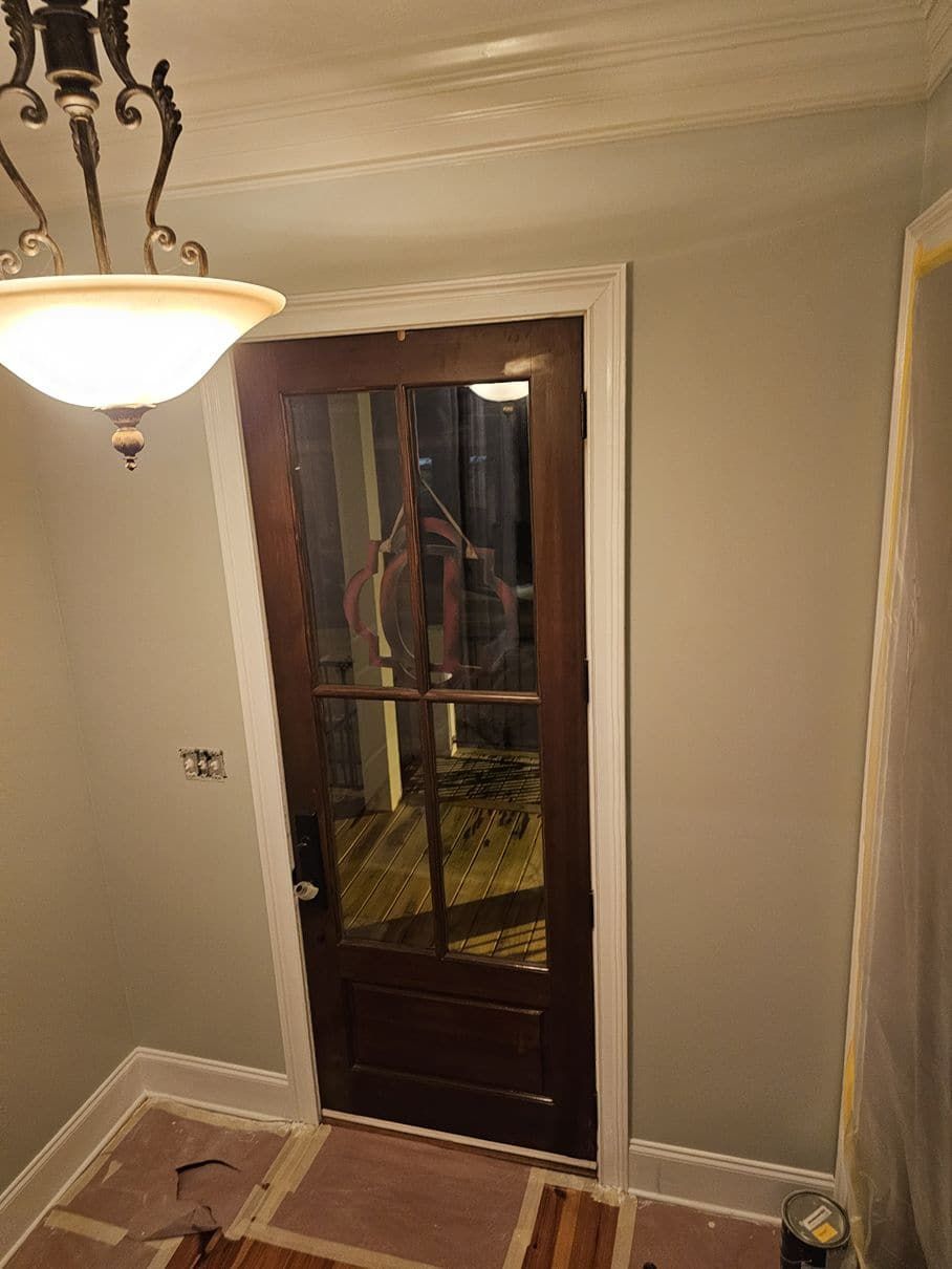 A door with a mirror on it is in a room with a chandelier.