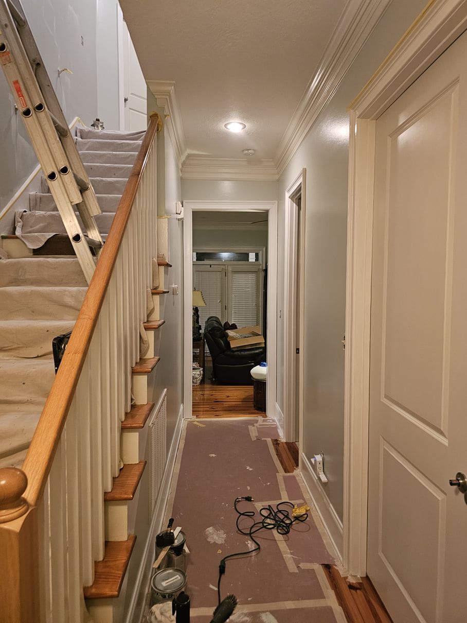 A hallway with stairs and a ladder in it.
