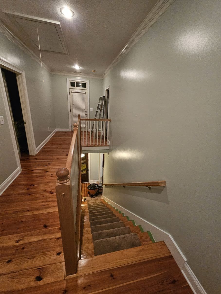 A hallway with wooden floors and stairs leading up to the second floor.