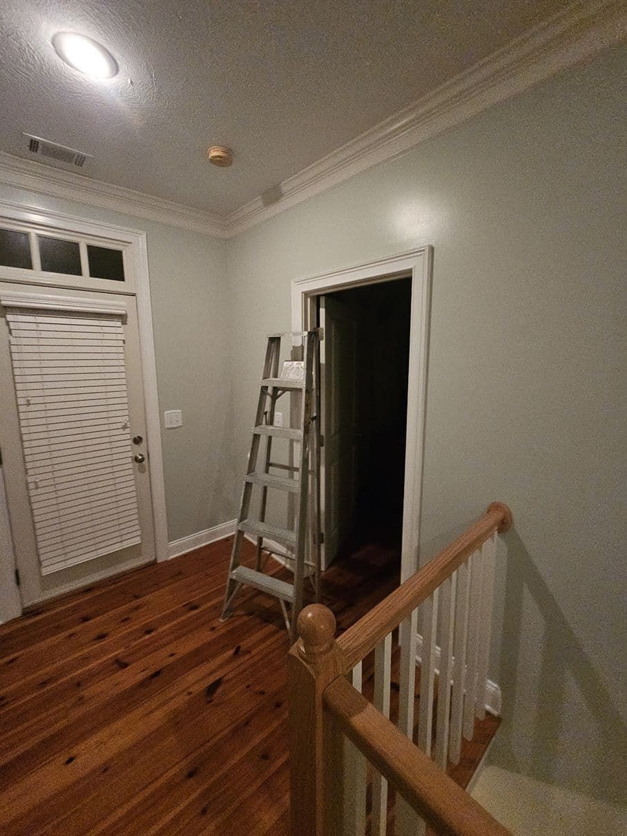 A ladder is sitting in a hallway next to a door.