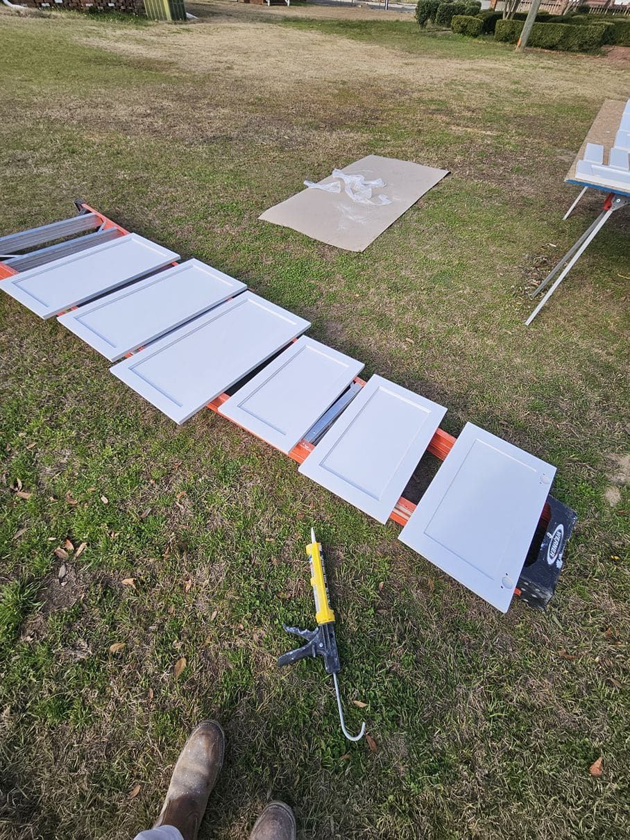 A person is laying on the grass next to a bunch of cabinet doors.