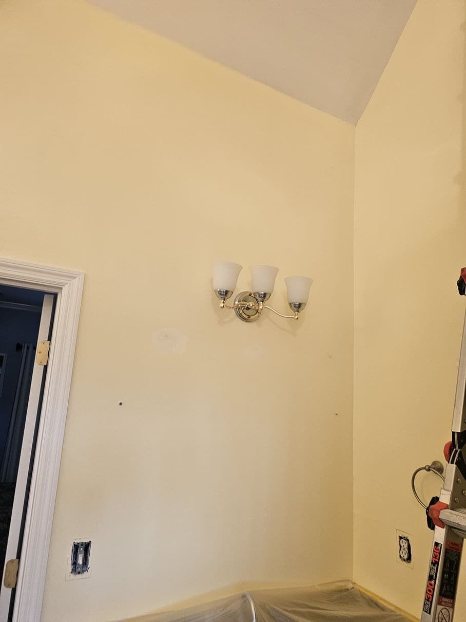 A room with a ladder and a lamp on the wall.