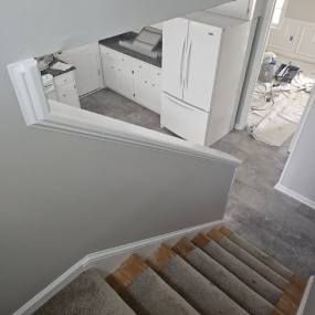 A view of a kitchen from the top of a set of stairs.