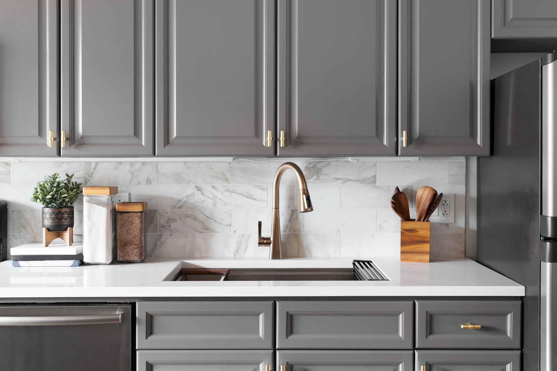 A kitchen with gray cabinets , a sink , a refrigerator , and a dishwasher.