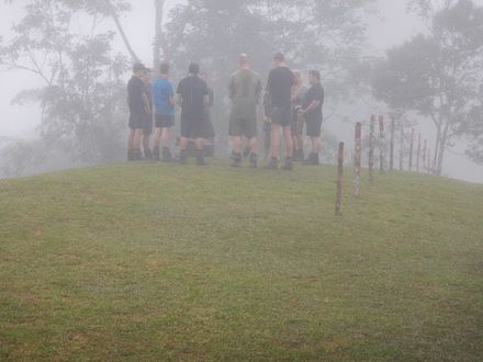 A group of trekkers standing in a circle during a minutes silence at the top of Brigade Hill, the site of the Battle of Mission Ridge, Kokoda Track.