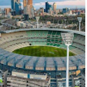 Overhead picture of the Melbourne Cricket Ground in the evening with the lights on.