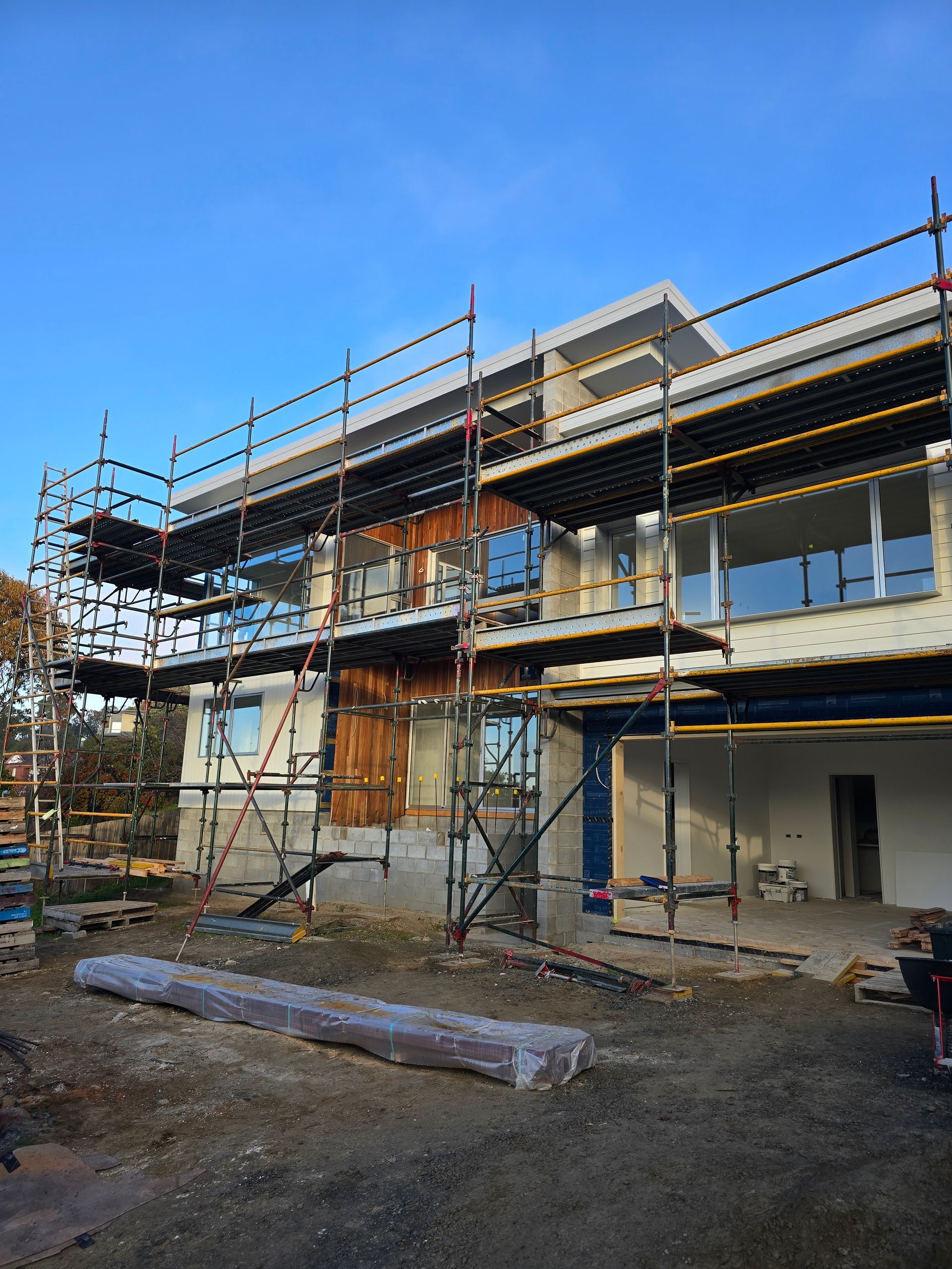 Two-story house under construction with scaffolding. 