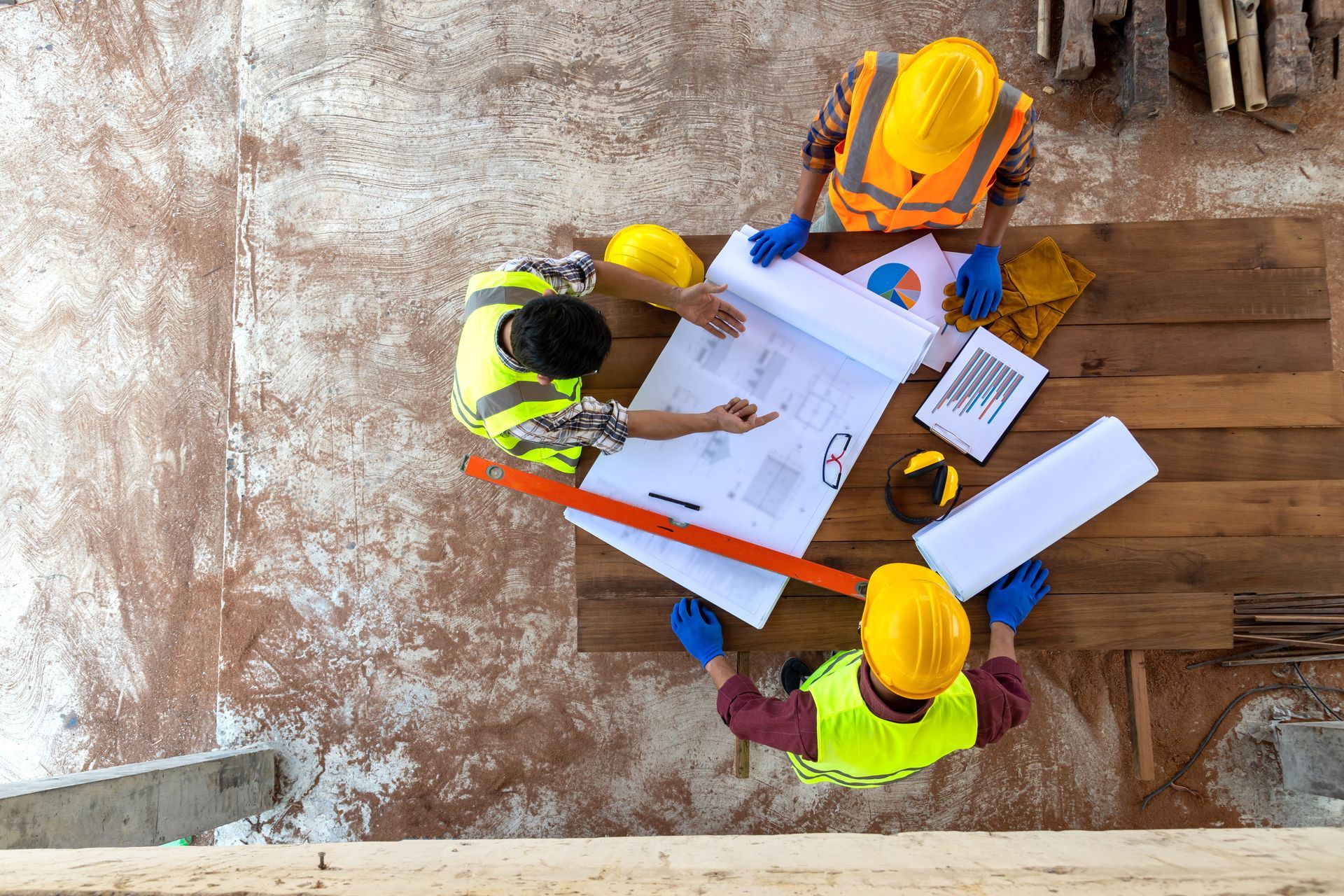 Aerial view of a team of three engineers and architects working on a construction site.