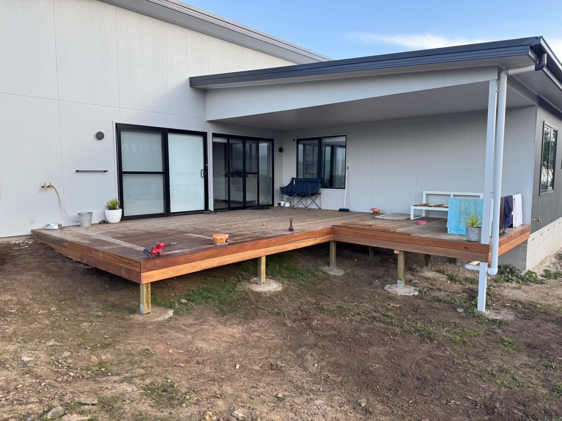 A partially constructed wooden deck attached to a light gray building.