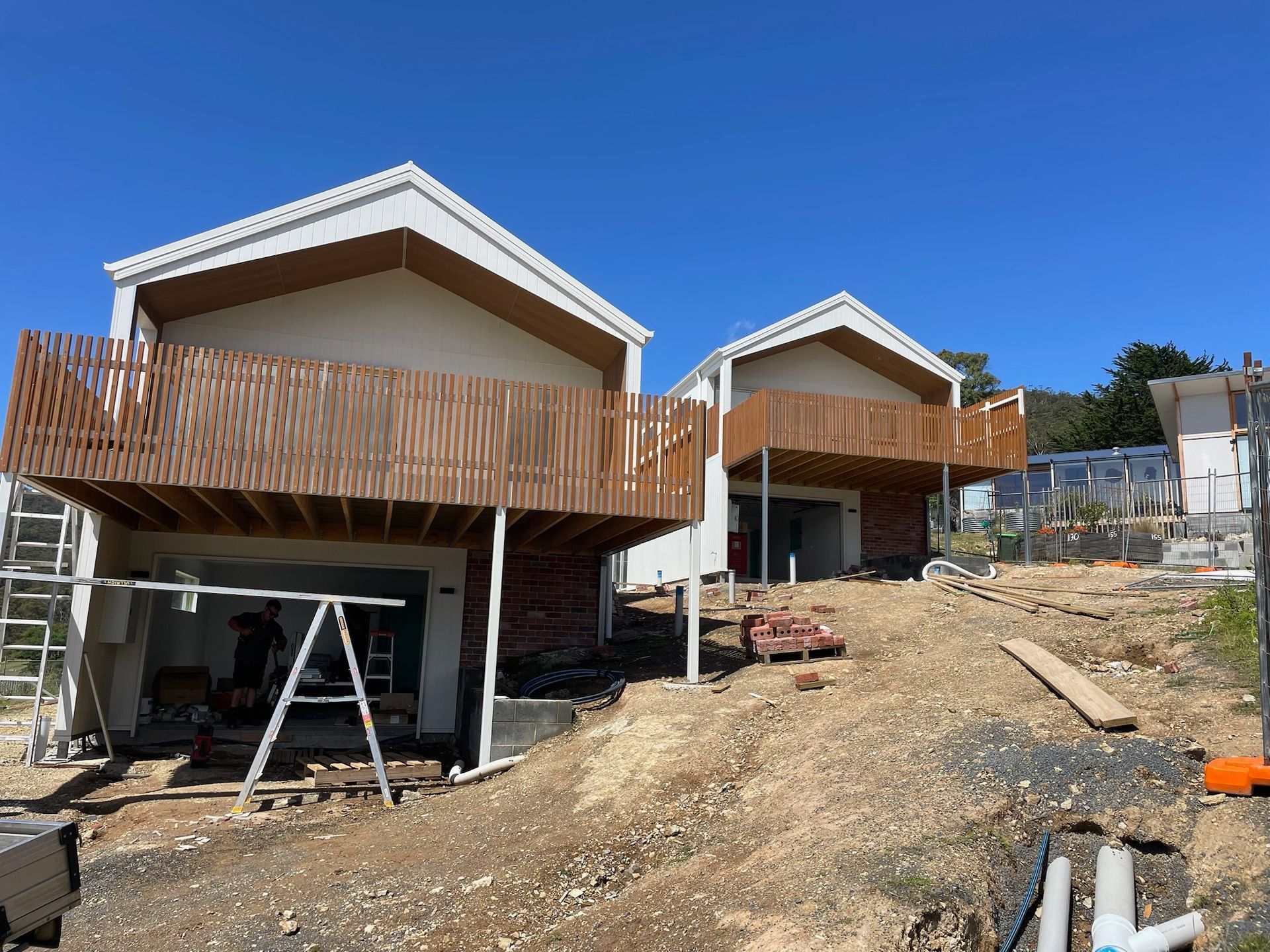 Two houses under construction, each with a brown wooden balcony.