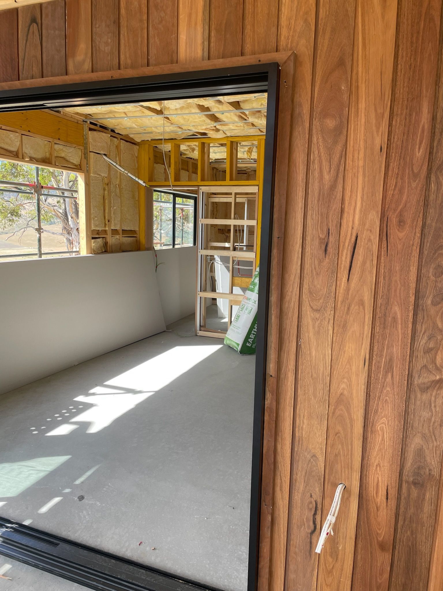 View through a doorway into a room under construction, featuring wood paneling and exposed framing.