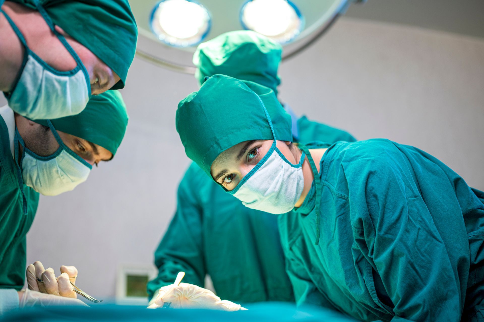 Vascular surgeons performing a surgical procedure in an operating room under bright surgical lights.