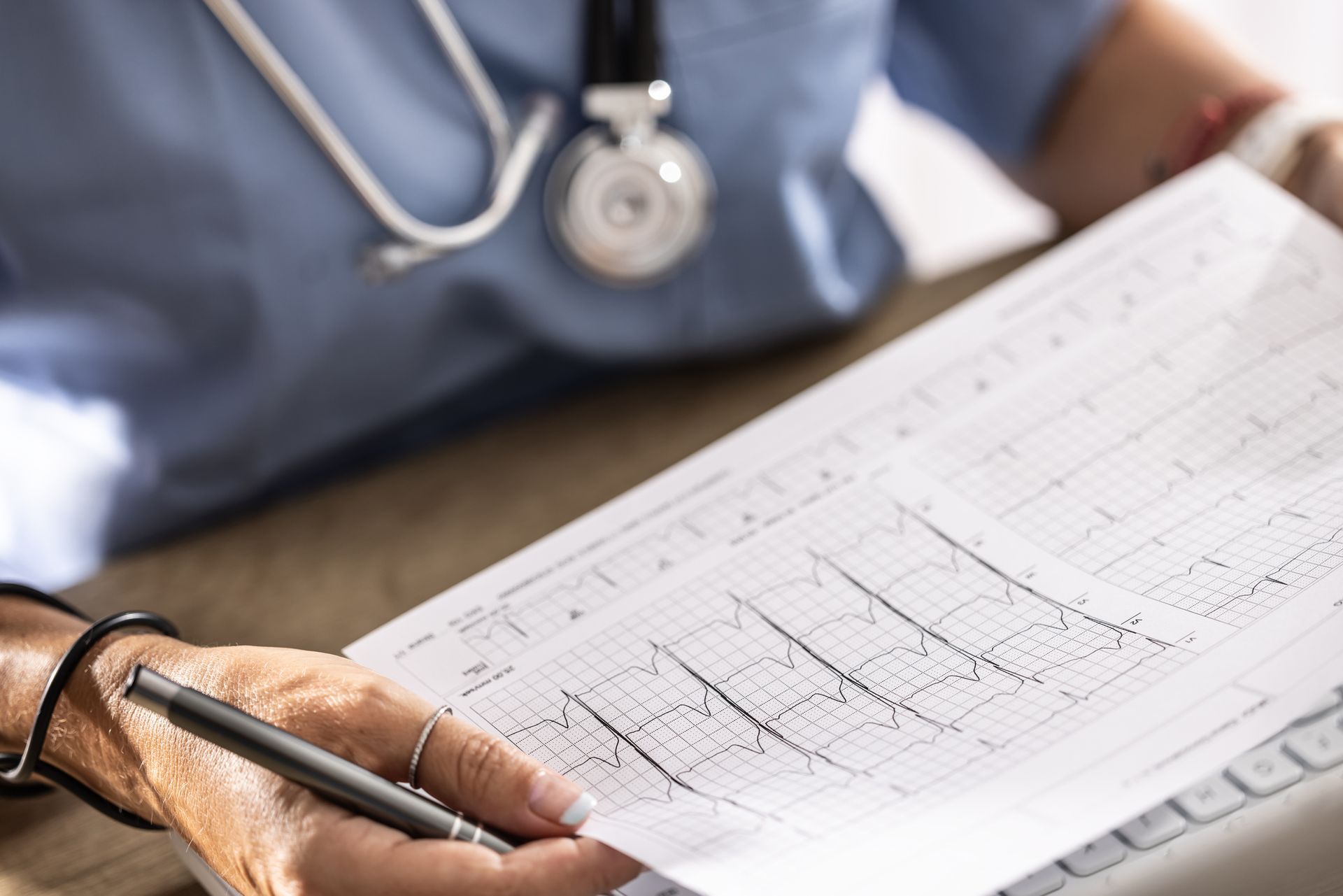 Doctor reviewing electrocardiogram printout while holding pen during evaluation.