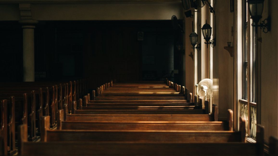 a row of wooden benches in an empty church .