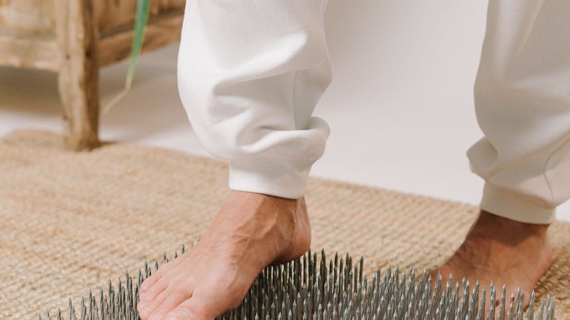 a person is standing on a mat with nails on it .