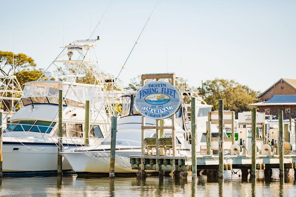 destin fishing fleet sign in front of parked boats at dock and marina