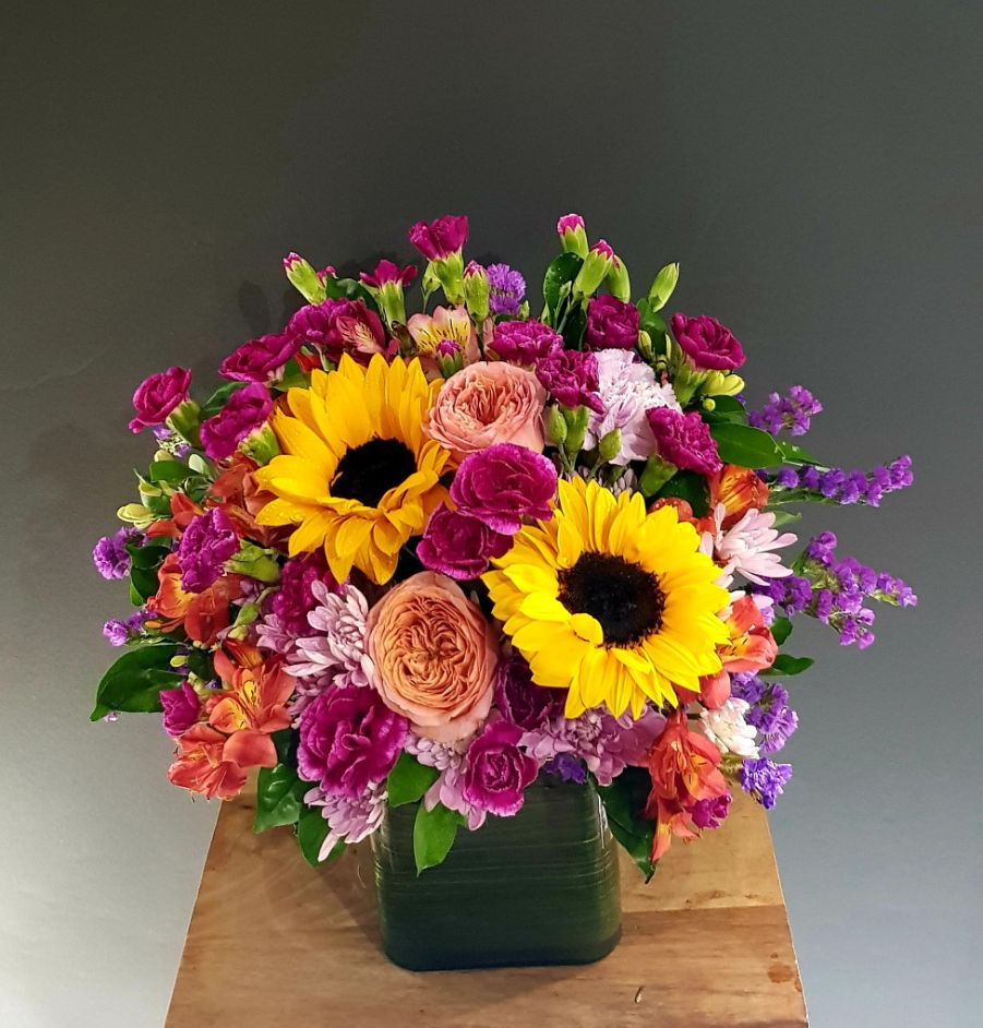 A Vase Filled With Purple and Yellow Flowers Sits on a Wooden Table — Greenfield Blooms and Gifts In Wanguri, NT