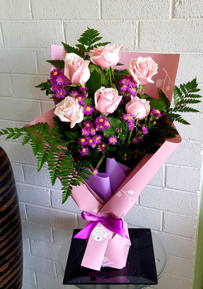 A Bouquet of Flowers Wrapped in White Paper With a Pink Ribbon — Greenfield Blooms and Gifts In Wanguri, NT