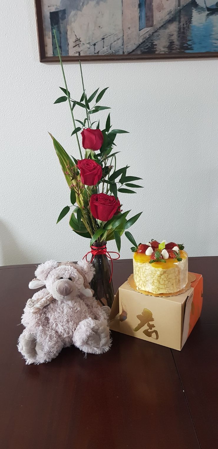 A Teddy Bear is Sitting on a Table Next to a Vase of Flowers and a Cake — Greenfield Blooms and Gifts In Wanguri, NT
