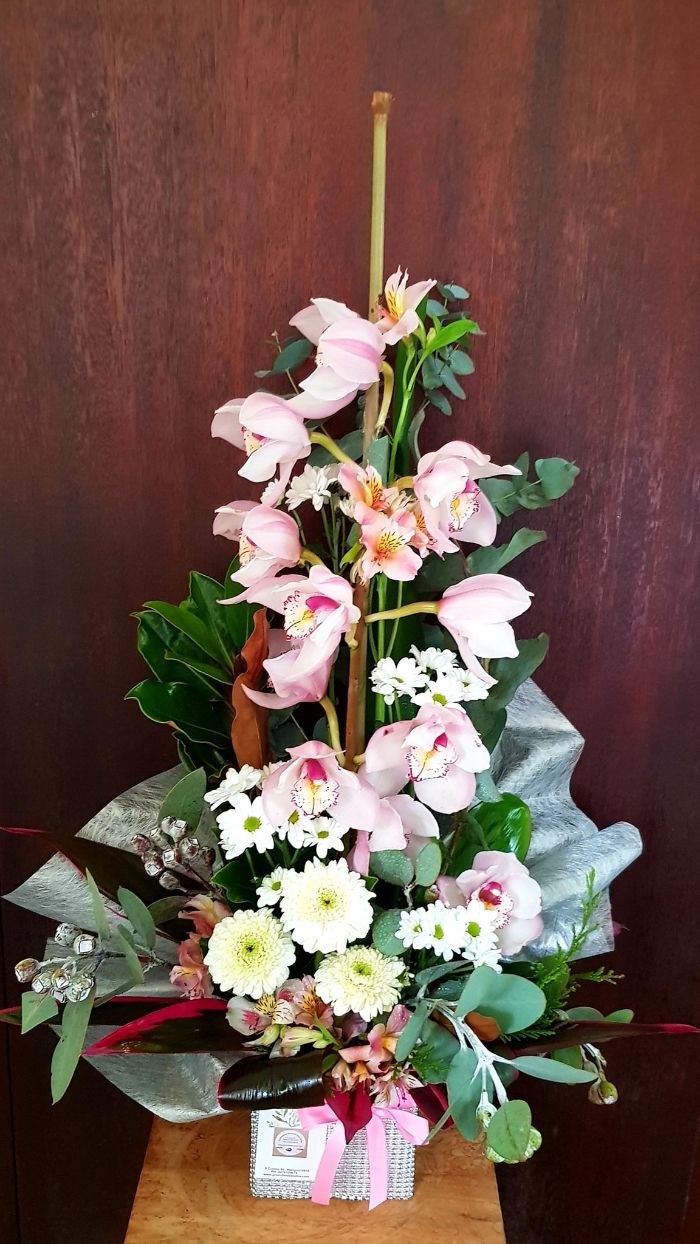 A Vase Filled With Pink and White Flowers is Sitting on a Wooden Table — Greenfield Blooms and Gifts In Wanguri, NT
