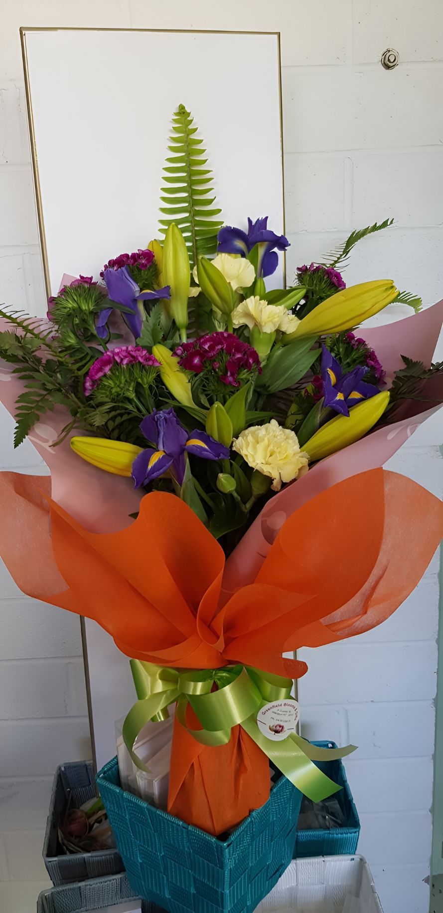 A Bouquet of Flowers Wrapped in Orange and Pink Paper is in a Blue Box — Greenfield Blooms and Gifts In Wanguri, NT