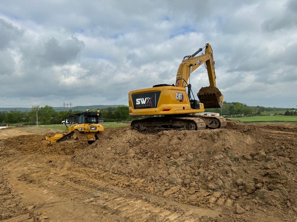 A bulldozer and an excavator are working on a dirt field.