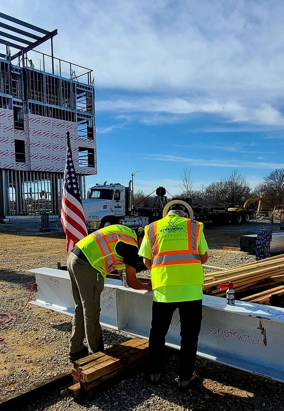 A couple of construction workers standing next to each other on a construction site.