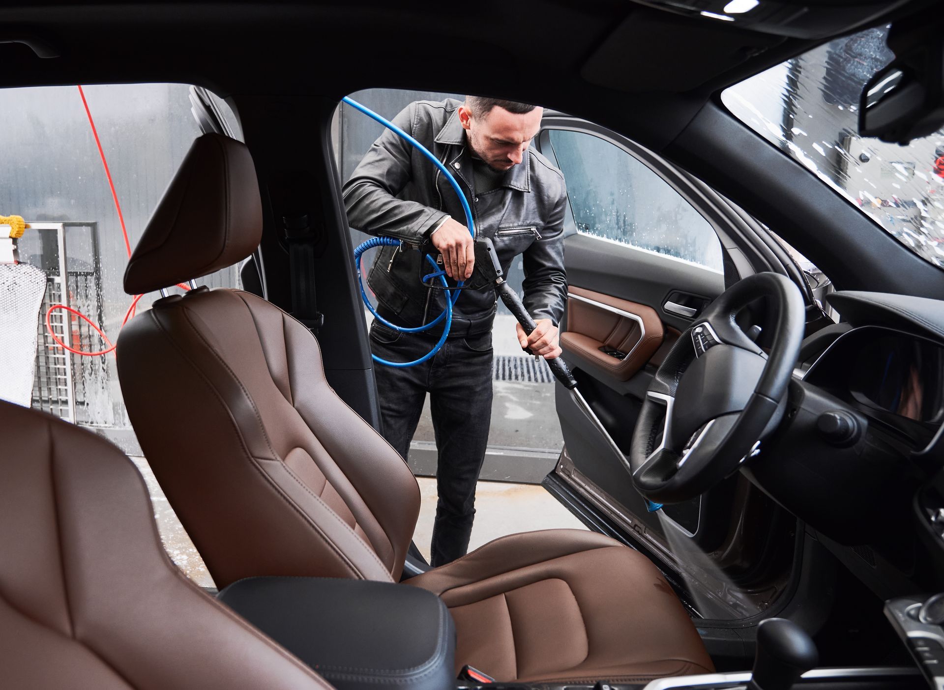 A man is cleaning the interior of a car with a vacuum cleaner.