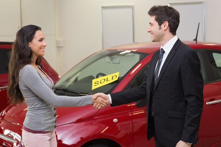 a man in a suit and tie is leaning against a red car .