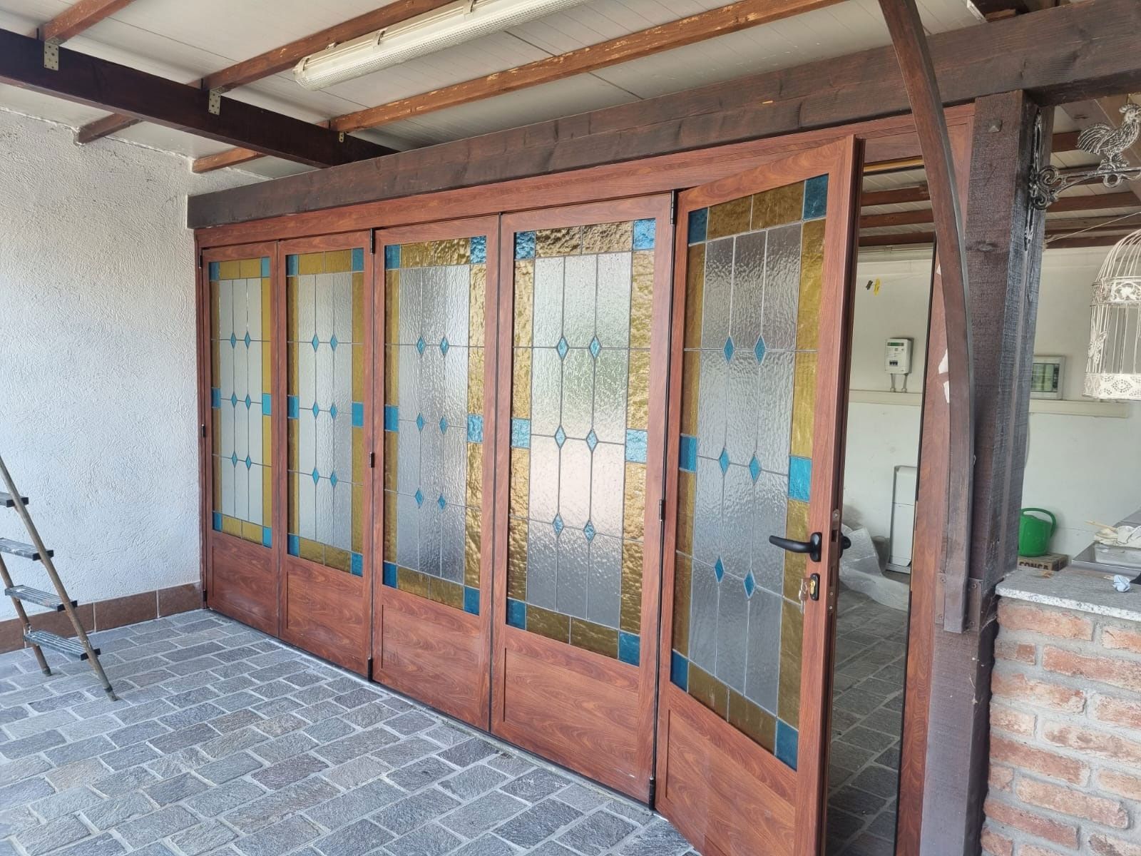 Porte pieghevoli in legno con pannelli in vetro colorato.