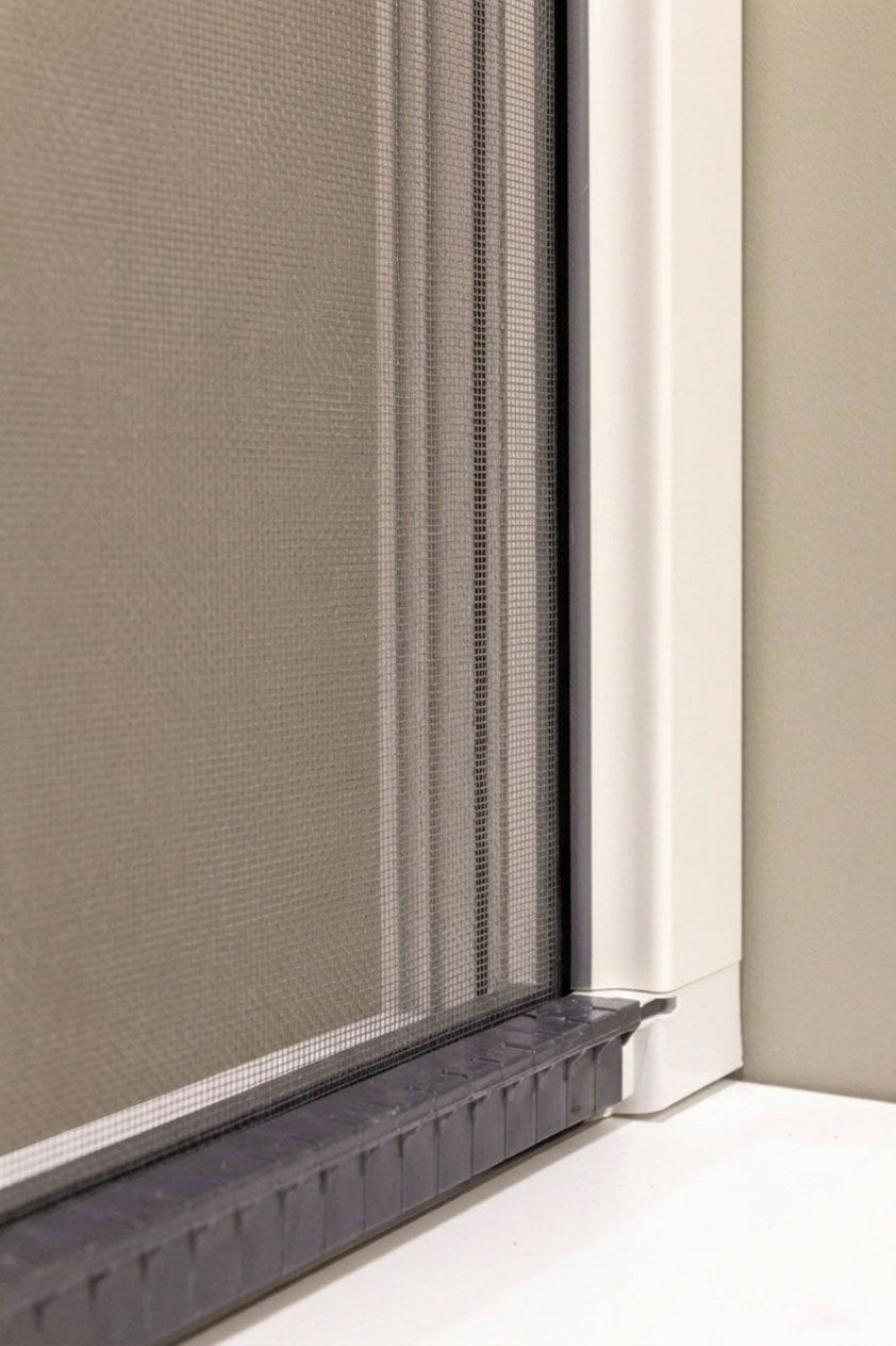 Vista attraverso una finestra di un condominio. Sono visibili edifici e vegetazione.