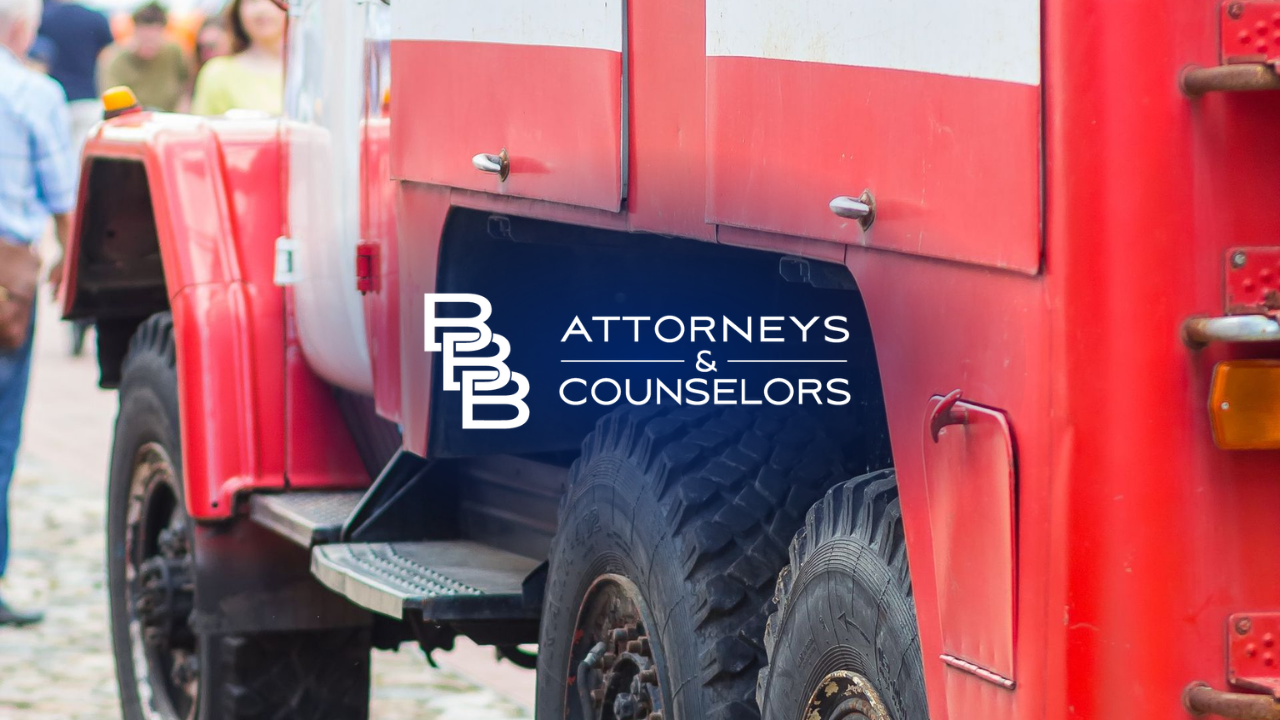 Red truck with “Attorneys & Counselors” logo parked on a street, blurred pedestrians in background