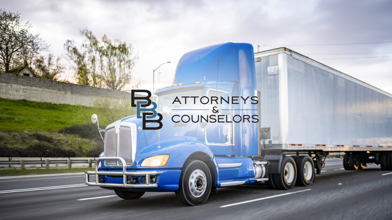Blue semi-truck hauling a silver trailer on a highway, with “Attorneys & Counselors” logo on the cab