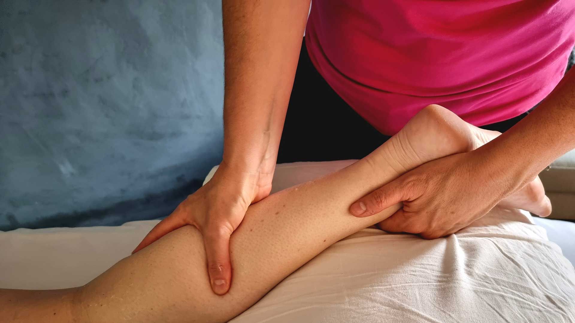 A woman is giving a leg massage to another woman.