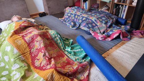 A person is laying on a bed with blankets and a yoga mat.