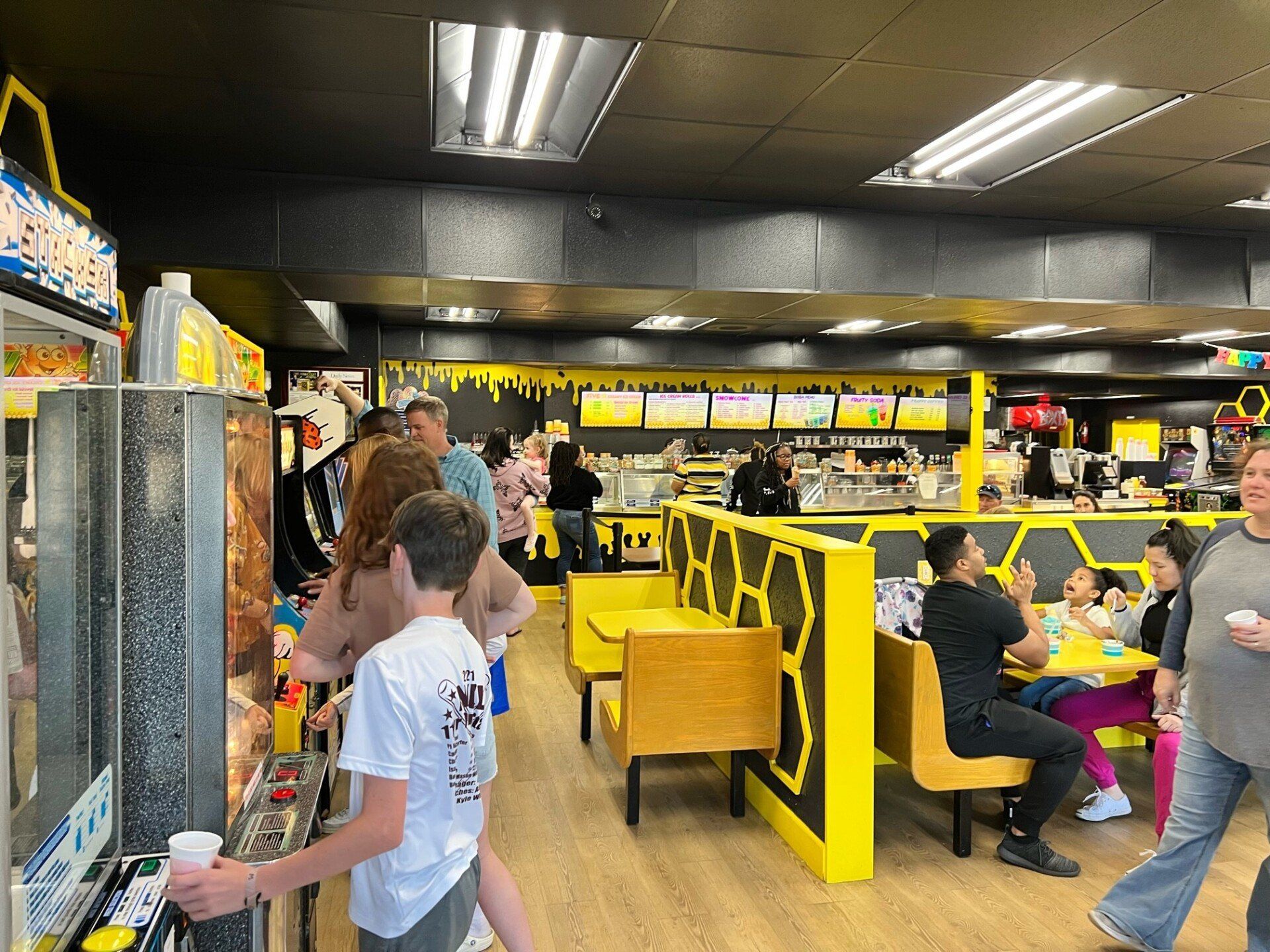 Kid Playing In Arcade Machine While Holding Cup - Niceville, FL - Honeybee Ice Cream & Arcade